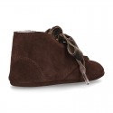 Suede leather little bootie for babies with velvet ties closure and fringed design.