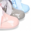 Patent leather little bootie for babies with silk ties closure design.