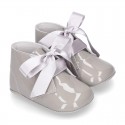 Patent leather little bootie for babies with silk ties closure design.