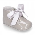 Patent leather little bootie for babies with silk ties closure design.