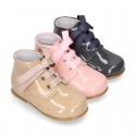 Classic pastel color patent leather ankle boots to dress with ties closure for first steps.