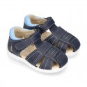 Washable leather kids sandal shoes with crossed straps and hook and loop strap closure.