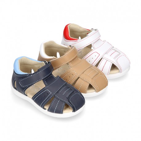 Washable leather kids sandal shoes with crossed straps and hook and loop strap closure.