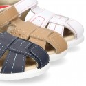 Washable leather kids sandal shoes with crossed straps and hook and loop strap closure.