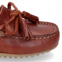 Moccasin shoes with bows and tassels in leather color for toddler boys.