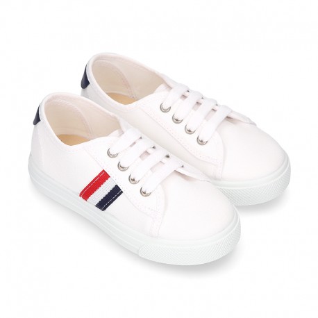 Cotton canvas kids tennis shoes to dress with shoelaces and flag design.