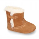 Baby bootie with hook and loop strap closure in suede leather.