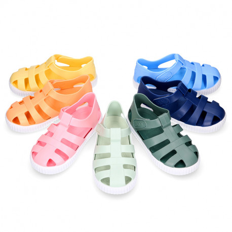 SNEAKER style kids jelly shoes with hook and loop strap in solid colors.