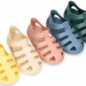 SNEAKER style kids jelly shoes with hook and loop strap in solid colors and matching soles.