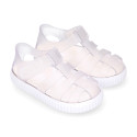 Tennis style kids jelly shoes with hook and loop strap and soles in colors.