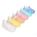 Tennis style kids jelly shoes with hook and loop strap and soles in colors.