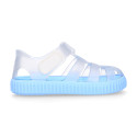 Tennis style kids jelly shoes with hook and loop strap and soles in colors.