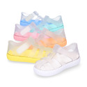 Tennis style kids jelly shoes with hook and loop strap and soles in colors.