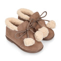 Booties with shoelaces closure with pompons and fake hair neck in suede leather for kids.
