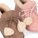 Booties with shoelaces closure with pompons and fake hair neck in suede leather for kids.