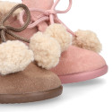 Booties with shoelaces closure with pompons and fake hair neck in suede leather for kids.