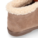 Booties with shoelaces closure with pompons and fake hair neck in suede leather for kids.