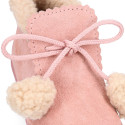 Booties with shoelaces closure with pompons and fake hair neck in suede leather for kids.