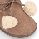 Booties with shoelaces closure with pompons and fake hair neck in suede leather for kids.