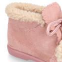 Booties with shoelaces closure with pompons and fake hair neck in suede leather for kids.