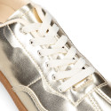Women's fashion sports shoe with laces in gold color.