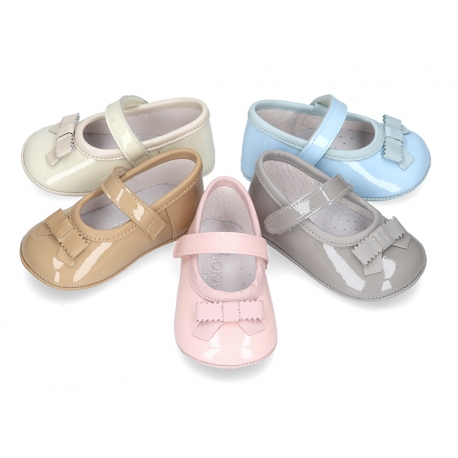 Classic little ballet flat shoes for babies with hook and loop strap and ribbon in patent leather.